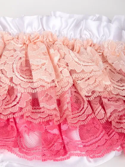 A macro shot of the delicate, layered lace on the ruffled diaper cover.