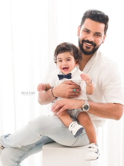 A proud father holds his laughing son. This light and airy portrait is a beautiful testament to the father-son bond.