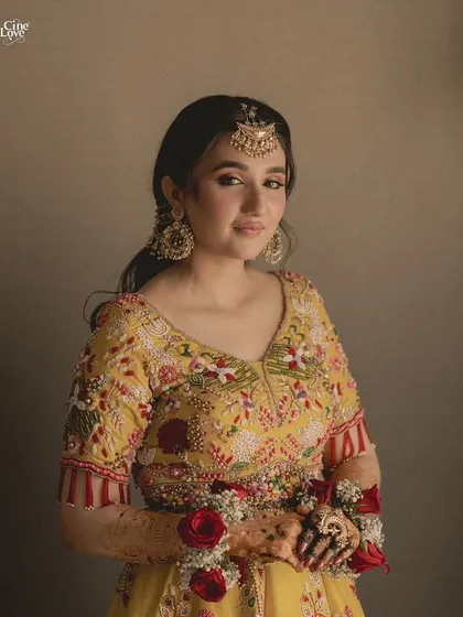 A portrait of the bride in her vibrant yellow floral lehenga, looking radiant and happy.