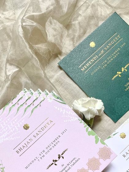 A set of elegant event cards with gold foil stamping. The designs for the Bhajan Sandhya and Mehendi & Sangeet use a combination of pink and emerald green, with traditional motifs for a classic look.