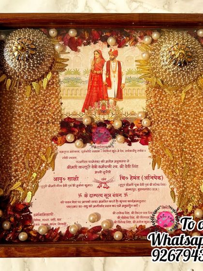 Another view of the wedding card, varmala, and kaleera frame, showcasing the beautiful illustration on the card and the arrangement of the preserved items.