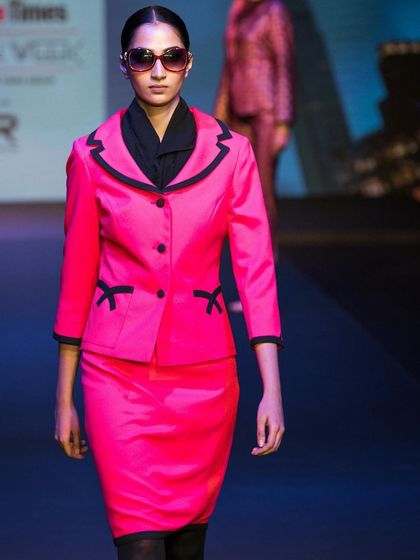 A shot from the ramp featuring a bright pink suit with black trim. My runway photography aims to capture the unique design details and color stories of each collection.