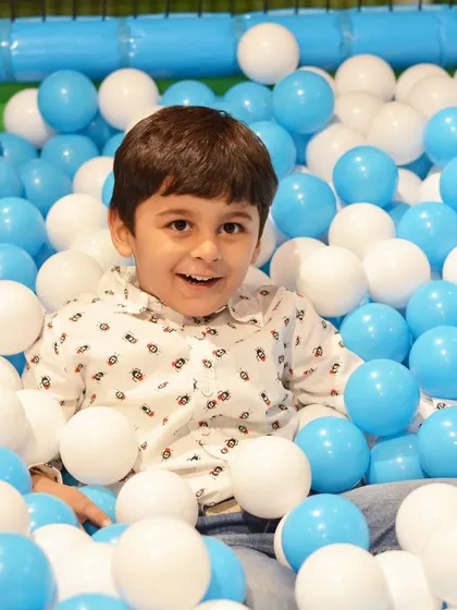 A happy toddler surrounded by blue and white balls in our mini ball pit. The simple color scheme is calming and fun.