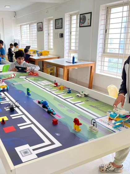 A wide view of our training center shows multiple teams preparing for the WRO national round. Each student is focused on their station, testing and refining their robots on the official competition mats.
