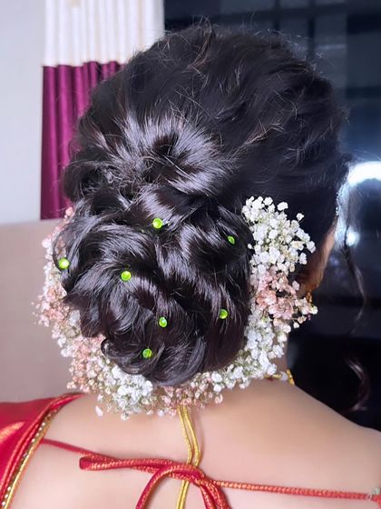 This simple twisted bun is perfect for an engagement bride. I've adorned it with a halo of baby's breath and small green studs, adding a delicate and fresh touch to the elegant updo.