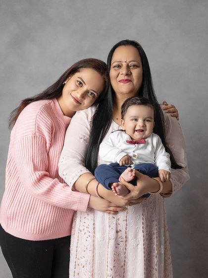 Three generations of women in one beautiful photo. A mother and grandmother smile lovingly with the family's newest baby, creating a touching legacy portrait.