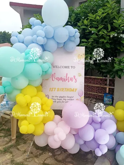 A cheerful welcome sign for Vamika's first birthday, surrounded by a rainbow of pastel balloons. This outdoor setup is perfect for a sunshine-themed party.