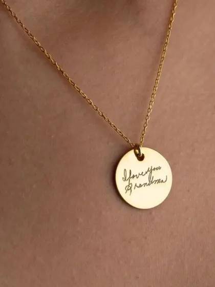Turn a cherished memory into a timeless keepsake. This round gold pendant is engraved with a loved one's actual handwriting, "I love you grandma", creating a uniquely personal and sentimental piece of jewelry.
