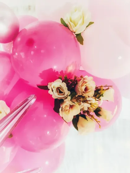A close-up showing the detail of adding artificial flowers to a balloon arrangement. These small touches add a layer of elegance and sophistication to the decor.