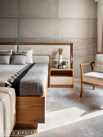 The guest bedroom at Noor Haus features a striking contrast between raw, concrete-finish wall panels and the warmth of the wooden bed frame. The design is minimal, peaceful, and perfectly balanced.