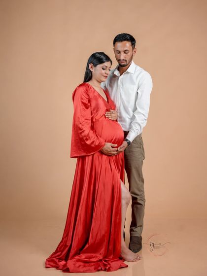 A tender moment captured against a simple, warm-toned backdrop. The focus here is purely on the couple and their connection as they await their baby.