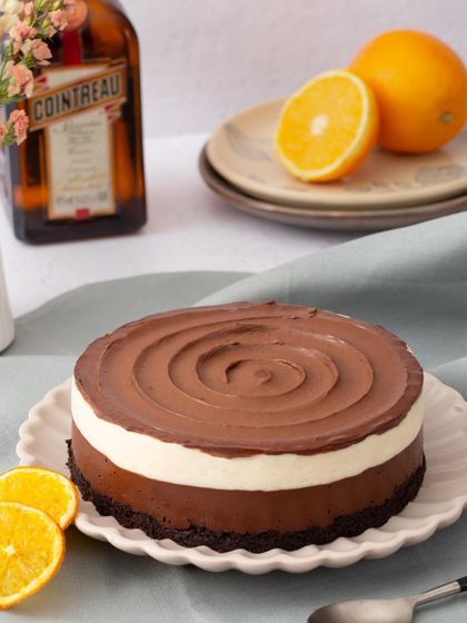 The full view of my dark chocolate and orange mousse cake, with its beautiful swirled ganache topping. The bottle of Cointreau in the background hints at its secret ingredient.