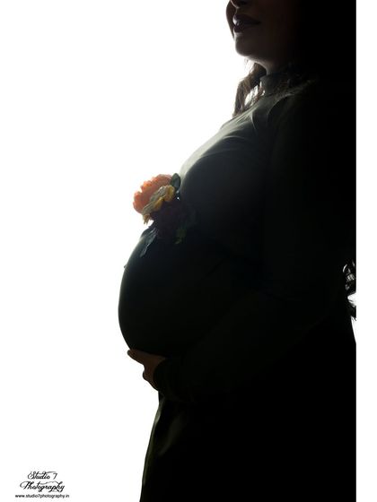 An artistic silhouette shot where the baby bump is adorned with a small flower. It's a creative and subtle way to add a touch of color and symbolism.