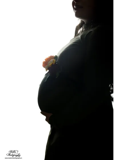 An artistic silhouette shot where the baby bump is adorned with a small flower. It's a creative and subtle way to add a touch of color and symbolism.