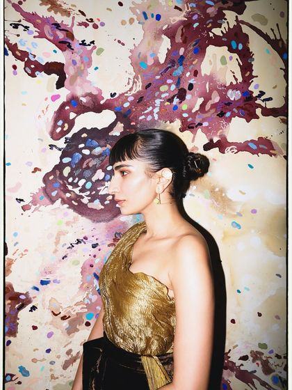 A profile shot against an abstract painting. The colors in the art complement the gold and brown tones of my outfit.