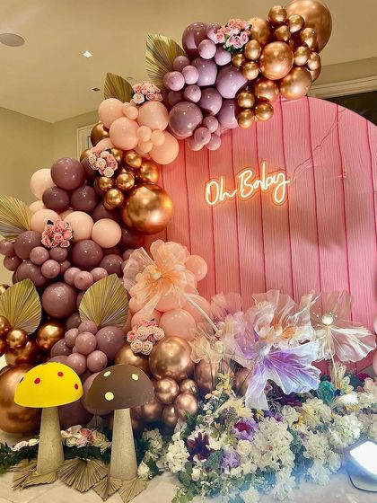 This image captures the full magic of the enchanted theme, from the glowing neon sign to the lush florals and whimsical props. It's a perfect backdrop for celebrating a special arrival.