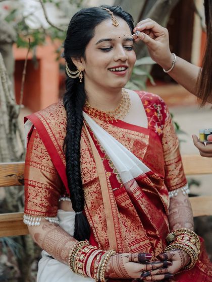 The color version of the same moment, showing a friend or family member applying a bindi to the bride's forehead.