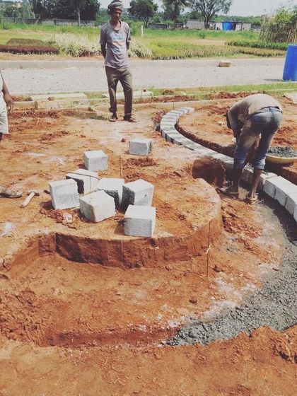 Workers constructing a curved stone border. This image captures the essential hands-on craftsmanship that is part of our design and building process.