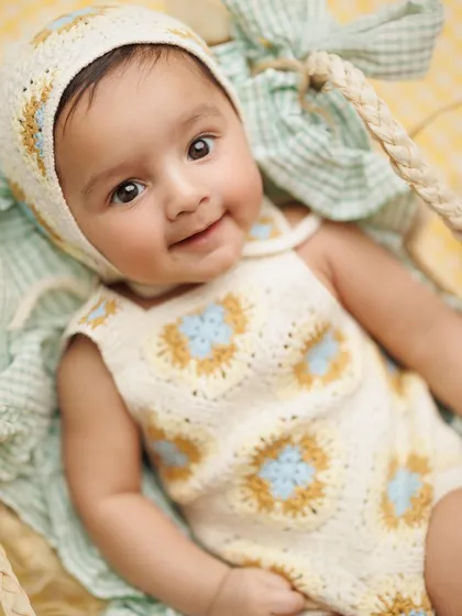 That sweet, knowing smile is just everything. This close-up from a milestone session shows the pure happiness of a baby in a cozy, handmade outfit.