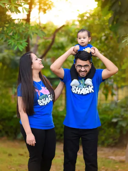 This family had fun with matching 'Daddy Shark' and 'Mommy Shark' shirts for their outdoor shoot. The baby on dad's shoulders is a classic, joyful pose.