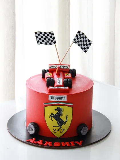 This bold red Ferrari cake features the iconic logo and an edible race car on top, perfect for a young racing fan.