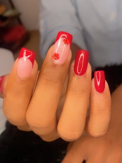 Flower nail art charms elevating a classic red French manicure.