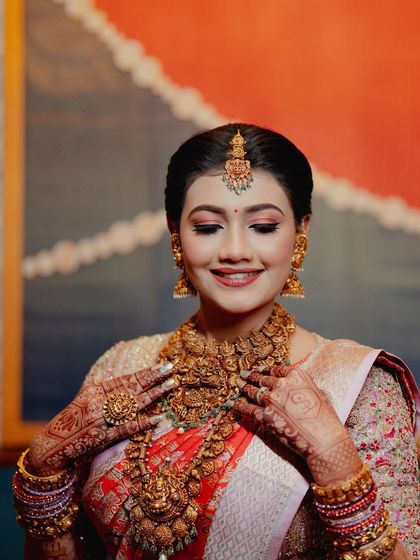 The bride looking down at her hands, a classic pose that highlights both her jewelry and her intricate mehendi.