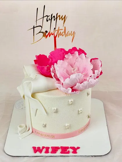 The perfect gift for your wifey. This elegant white cake is adorned with a stunning, oversized pink sugar peony and a delicate fondant ribbon.