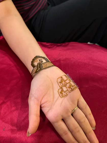 A minimalist approach, with the initial 'S' on the wrist and a small elephant motif on the palm, creating a delicate and meaningful design.