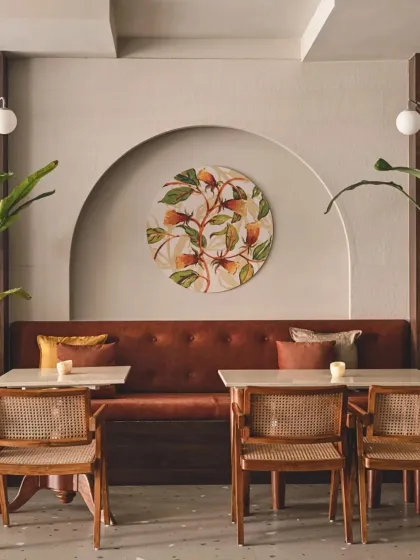 In our Bali-themed cafe, we used soft arched niches to create intimate seating nooks. Each niche is highlighted with hand-painted art, complemented by rattan chairs and terracotta upholstery to achieve a rustic yet contemporary balance.