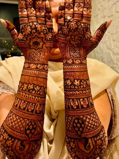 A full bridal design with dense, intricate patterns covering the hands and forearms. This style includes elephant motifs and detailed checkerboard patterns.