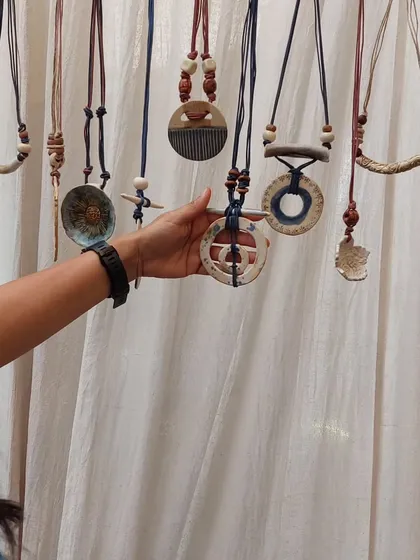 A customer browsing my collection of handmade ceramic necklaces at a market. Each one is strung with care and features unique, hand-formed beads and pendants.