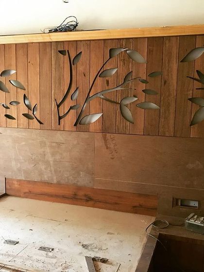 This image captures the creation of a custom wooden headboard. The intricate, laser-cut leaf and branch design adds a beautiful, organic element to the bedroom wall.