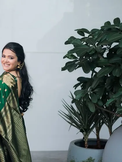 A beautiful bride in a dark green saree looks back with a smile.