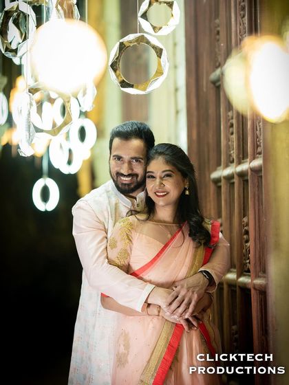 A happy portrait of a couple embracing, surrounded by modern, glowing light fixtures, perfect for an elegant evening shoot.