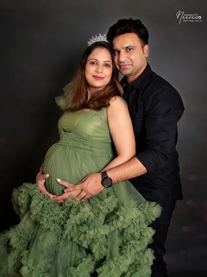A regal portrait for a glowing mother to be. Wearing a beautiful tiara and an olive green gown, she stands with her partner in a classic, elegant pose that celebrates this special time.