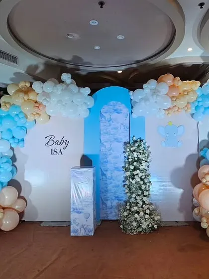 A grand balloon arch backdrop in a sky theme for "Baby Isa." The setup uses clouds of blue, peach, and white balloons to create a beautiful and dreamy effect.