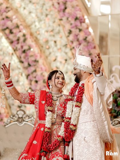 A moment of pure joy and celebration as the newly married couple raises their hands in triumph. The bride's radiant smile and their happy energy are infectious in this candid shot.