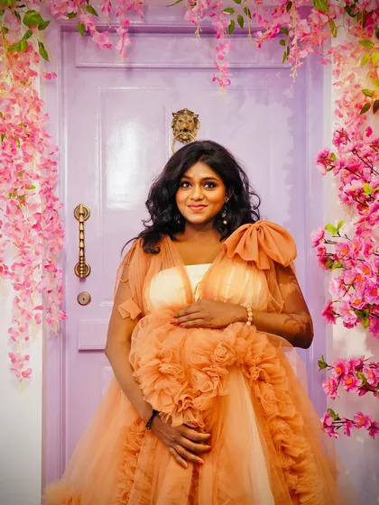 A beautiful solo portrait of a mom-to-be in a peach ruffled gown. The soft color of the dress works perfectly with the lavender floral door, creating a dreamy and feminine look.