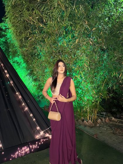 Another full shot of the purple saree, holding a golden clutch. The entire look is chic and sophisticated.