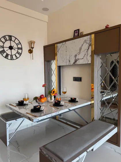 Here is one of my favorite innovations: a space-saving dining table that folds away neatly. This unit features a marble-finish tabletop, bench seating, and decorative mirror panels, making it perfect for compact Mumbai apartments.