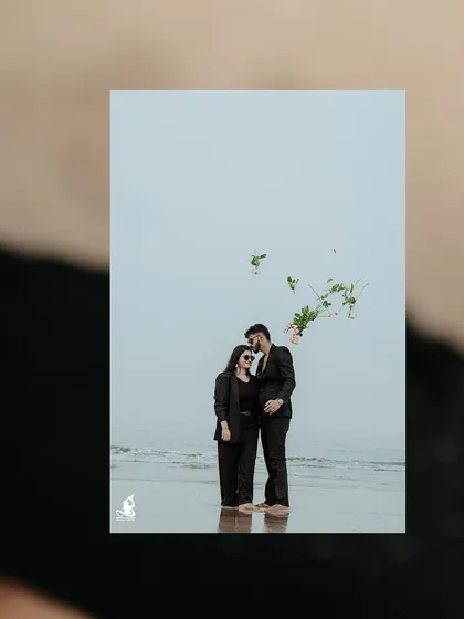 A creative shot of a couple on the beach, with a bouquet of flowers seemingly floating in the air.