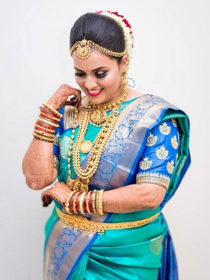 This bride is a vision in blue and gold. Her makeup features a sharp, defined eye and a bright smile, capturing the joy of her wedding day.