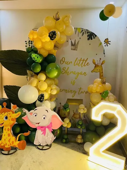 My jungle theme setups are a big hit with the kids. This one features cute elephant and giraffe cutouts, a personalized backdrop, and a big light-up number '2' for the birthday boy.