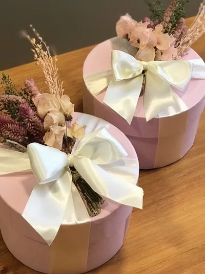 An example of our custom packaging for bridesmaid hampers. These beautiful pink hat boxes are adorned with dried florals and a satin ribbon, creating a truly special gift for your bride tribe.