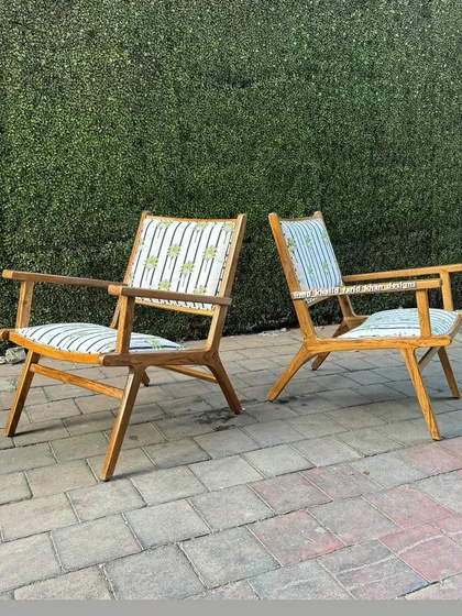 A pair of mid-century easy chairs with a distinctive X-frame, upholstered in a patterned fabric.