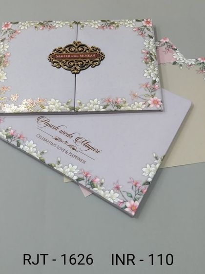 A sweet gate-fold invitation in pastel purple with a border of small pink and white flowers. The wooden nameplate adds a charming, rustic touch.