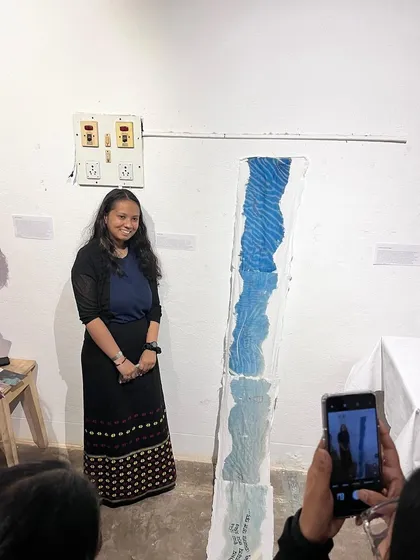 An artist proudly stands next to her work during an open house event. We provide a clean, professional gallery setting with white walls and track lighting, making it an ideal space for artists to showcase their creations to an engaged audience.