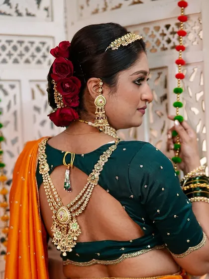 A view of the complete look from the back, highlighting the stylish blouse and the intricate hairstyle adorned with fresh roses. Every detail contributes to the overall artistic vision.