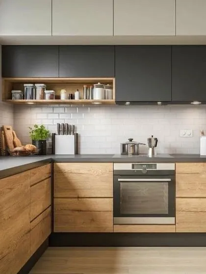 A two-tone kitchen design combining natural wood lower cabinets with matte black uppers for a bold, contemporary look. An open wooden shelf provides easy access to spices, while under-cabinet spotlights illuminate the work surface.